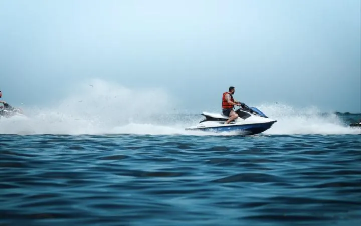 Rider in a life jacket on a jet ski throwing up spray
