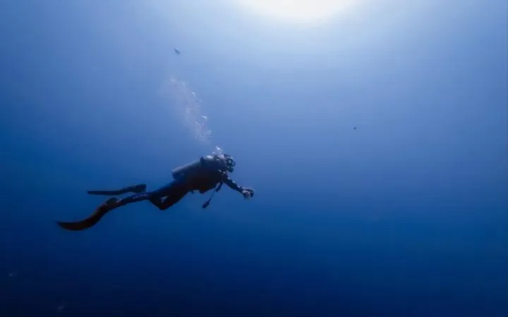 Scuba diver swimming through deep blue water